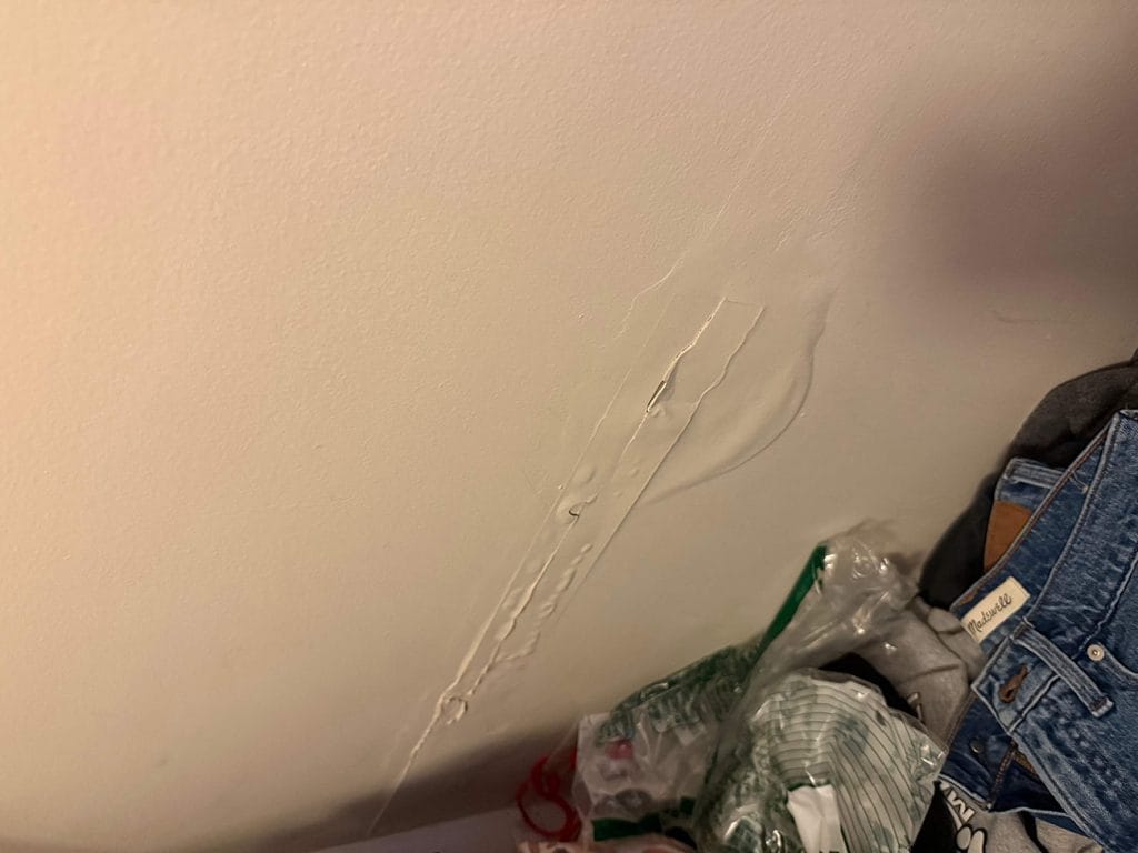 Water damage bubble on bathroom ceiling caused by roof leak from missing step flashing
