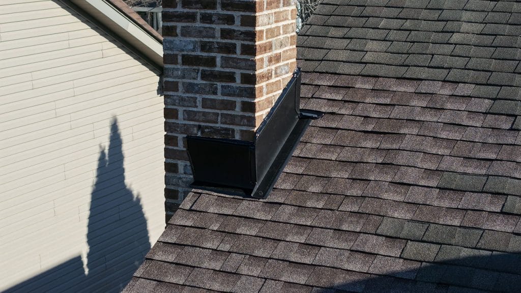 Completed chimney repair with new step flashing, counter flashing, and shingles